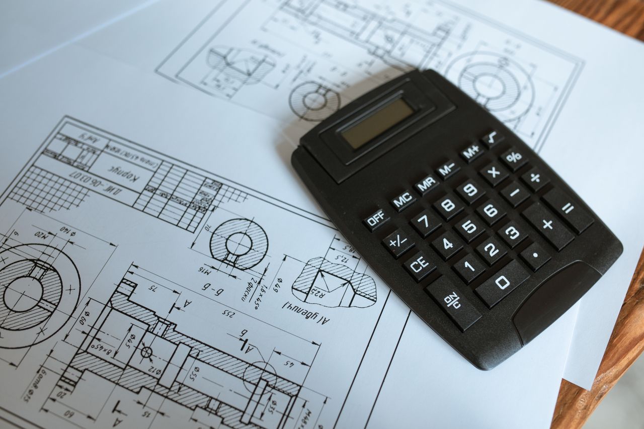 Close-up of a calculator resting on technical engineering blueprints, showcasing precise calculations.